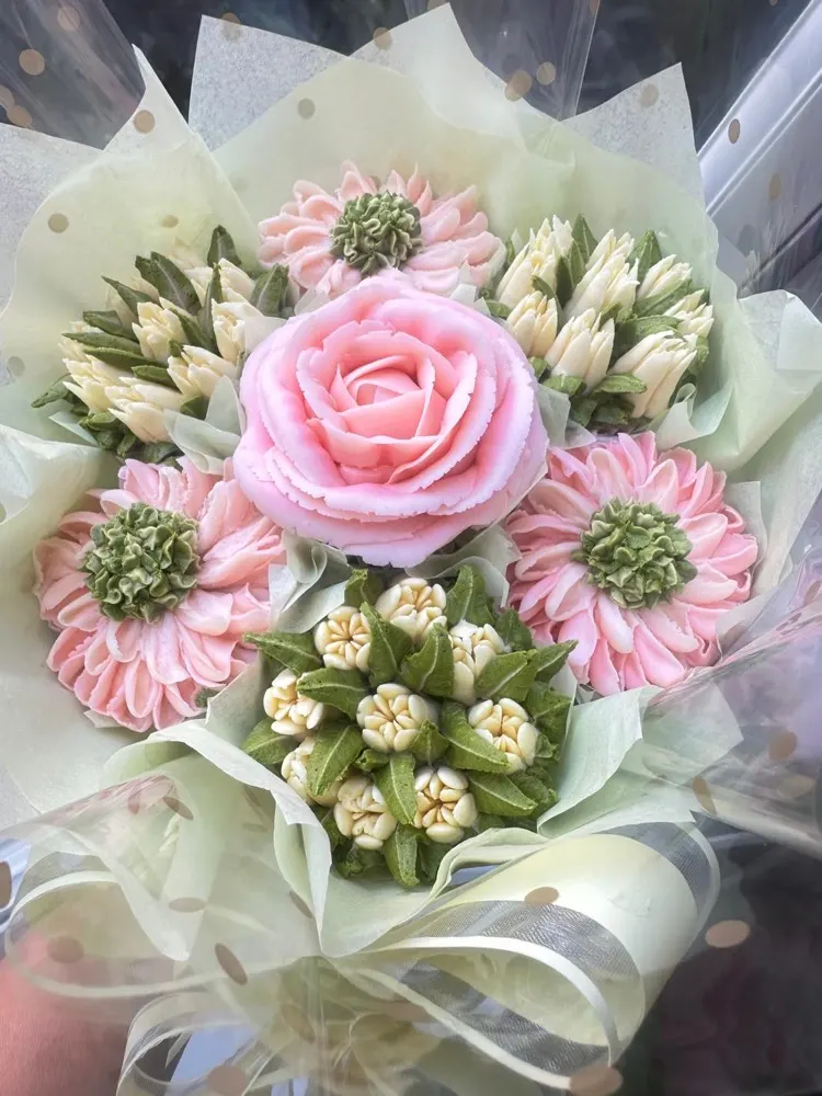 Classic cupcake bouquet with a pink rose centrepiece and pastel buttercream daisies